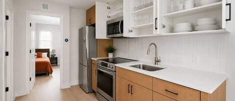 A modern kitchen with stainless steel appliances, wooden cabinets, and a white countertop.