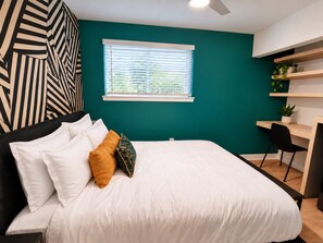 Ein Schlafzimmer mit einem Bett, Kissen, einem Schreibtisch und einem Stuhl.