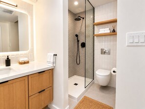 Ein modernes Badezimmer mit einer Duschkabine, einer Toilette und einem Waschtisch mit Spiegel.