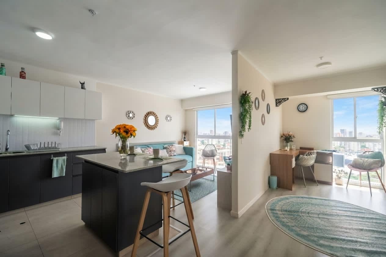 A modern kitchen with a central island, bar stools, and a view of the city.