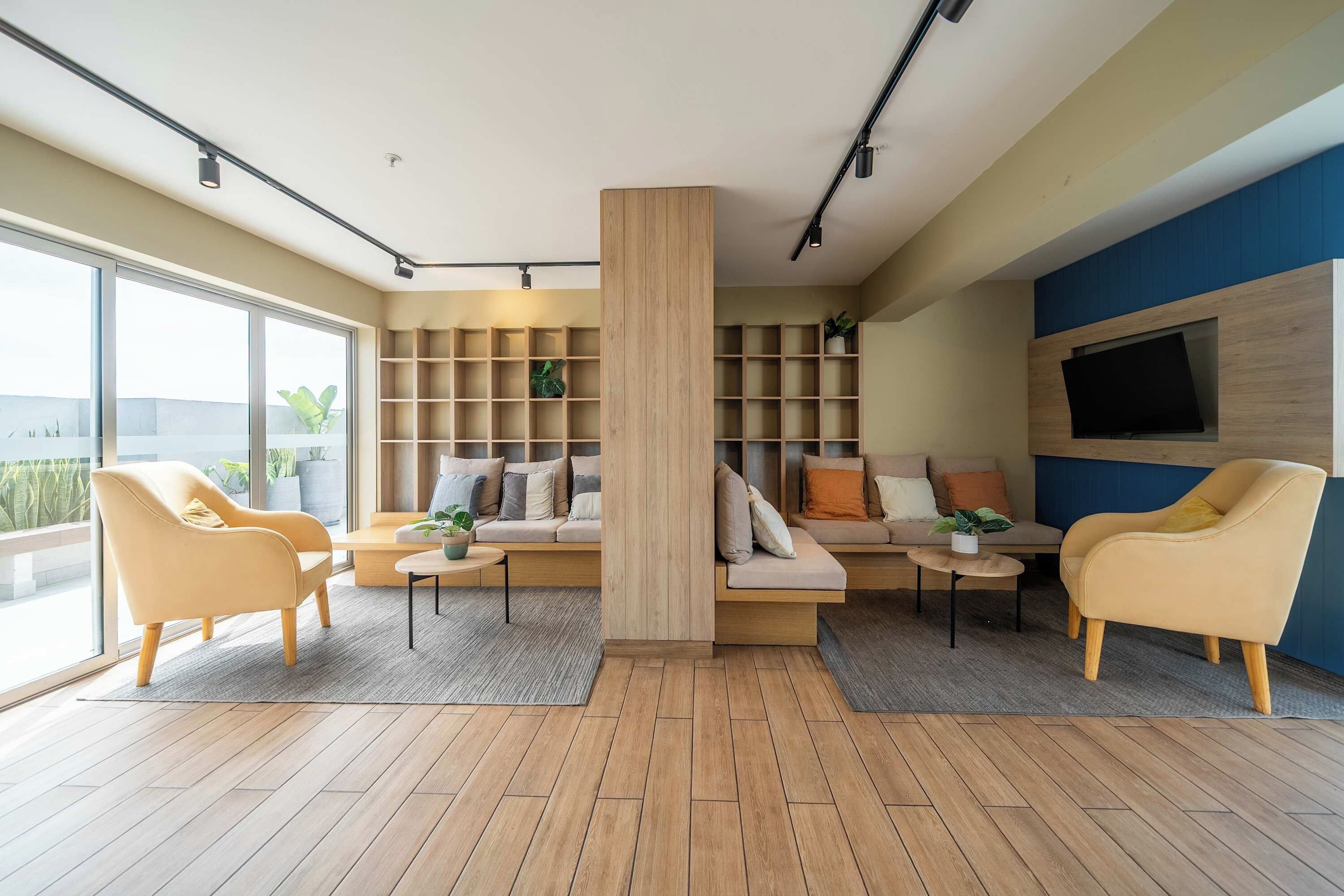 Un salon moderne comprenant un canapé, deux fauteuils, une table basse et des étagères intégrées.