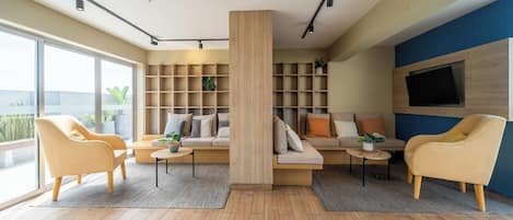 A modern living room with a sofa set, two armchairs, a coffee table, and built-in shelving.
