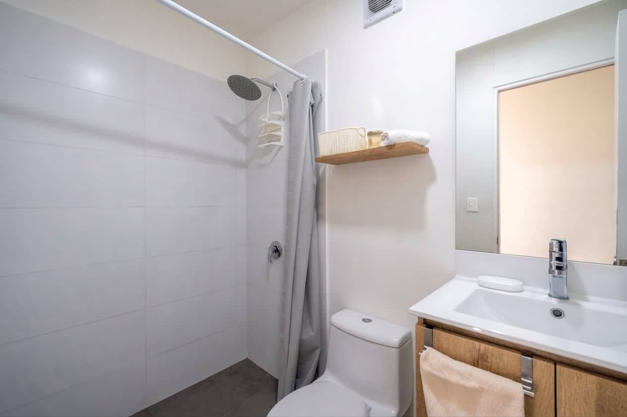 A modern bathroom with a shower, toilet, sink, and a mirror.