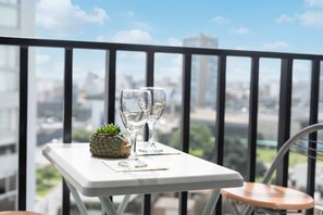 A balcony with a table, two glasses, and a small plant. - La Buenavista Prado Residences (La Victoria)