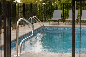 A swimming pool with metal handrails, surrounded by a fence and white lounge chairs. - Heated Pool, Hot Tub, Fire Pit & Outdoor Theater - Asheville" (Fairview)