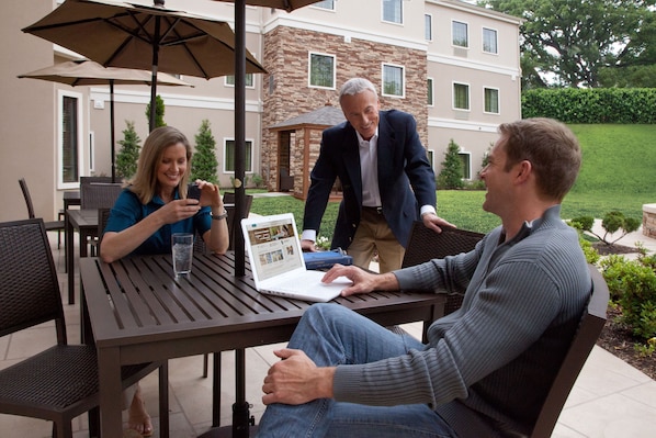 A patio with a table, chairs, and a laptop.