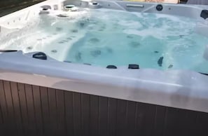 A hot tub with a wooden deck surrounding it.