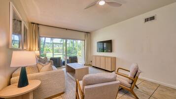 Una sala de estar moderna con sofá, sillón, mesa de centro y televisor montado en la pared.