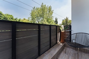 A balcony with a dark wooden fence, a potted plant, and a black chair. - Suite with a Balcony | Polanco | Relax (Ciudad de México)