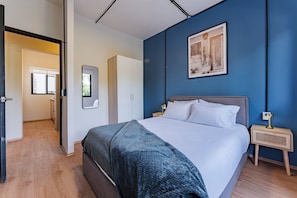 A bedroom with a bed, a nightstand, a mirror, and a door leading to a bathroom. - Suite with a Balcony | Polanco | Relax (Ciudad de México)
