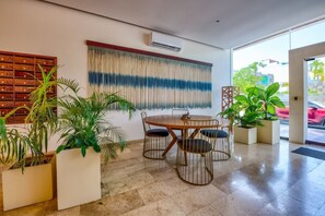 A modern interior with a round table and chairs, a wall-mounted air conditioner, and potted plants. - Ipana 1BR | Rooftop Pool & Parking | Near 5th Ave (Playa del Carmen)
