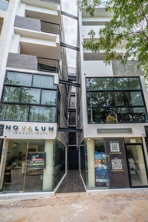 A modern building with a storefront labeled 'NOVALUM' and a 'LEGAL CONSULTANCY' sign. - Stylish 2BR Condo, Hot Tub, Gym & Rooftop Pool (Tulum)