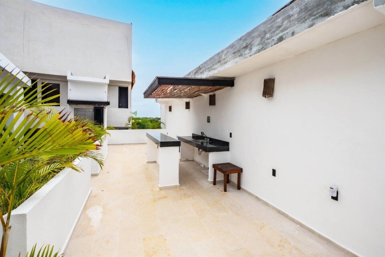 A modern outdoor kitchen area with a built-in sink and a small wooden stool.