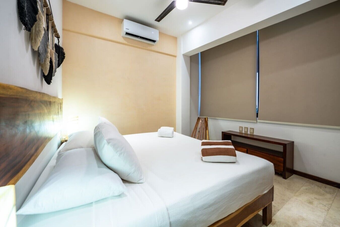 Ein Hotelzimmer mit einem Bett, Kissen, einem Nachttisch, einer Klimaanlage und einem großen Fenster.
