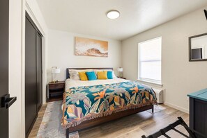 A bedroom with a bed, nightstands, a window, and a painting on the wall. - Seaside Nest-Cozy Coastal Retreat in Beautiful Brookings, Oregon (Brookings)