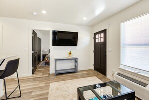 A modern living room with a flat-screen TV, a coffee table, and a sofa. - Seaside Nest-Cozy Coastal Retreat in Beautiful Brookings, Oregon (Brookings)