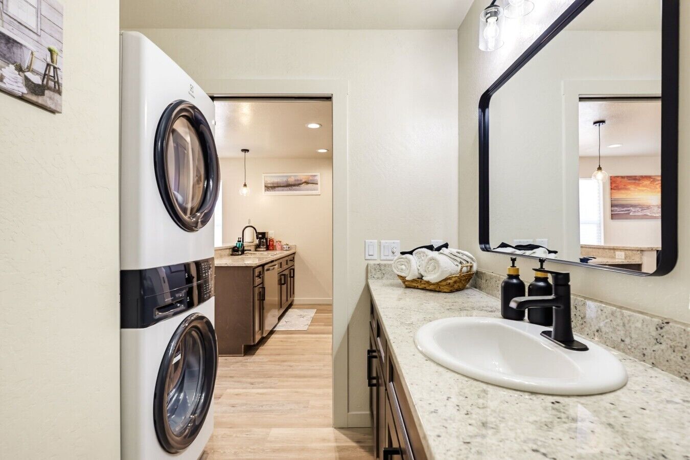 A compact laundry area with a washing machine, a sink, and a mirror.