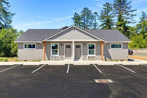 A building with a gabled roof, a front porch, and a parking lot. - Seaside Nest-Cozy Coastal Retreat in Beautiful Brookings, Oregon (Brookings)