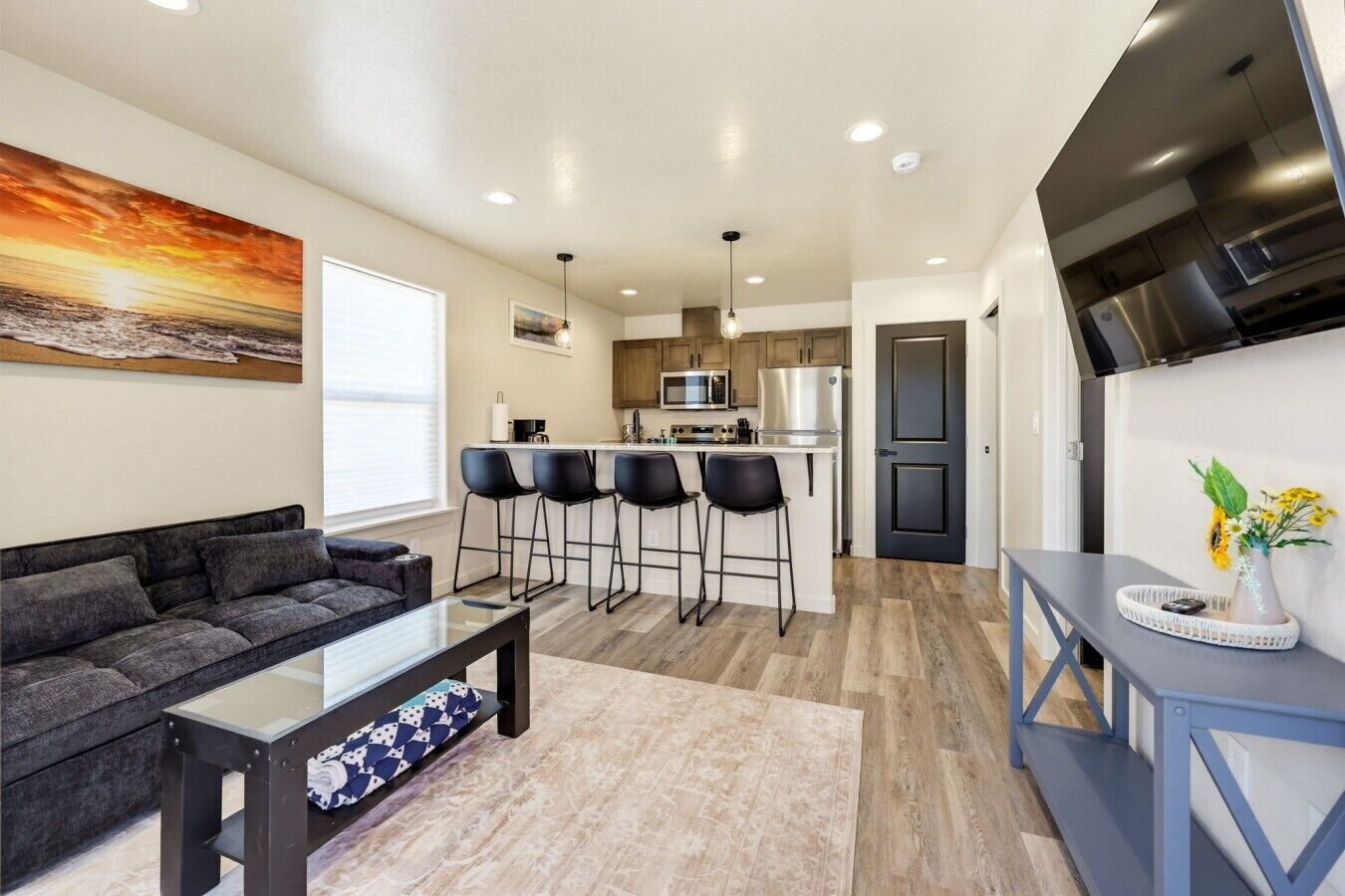 Una sala de estar moderna con un sofá, una mesa de centro y una zona de cocina con un juego de taburetes de bar.