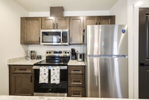 Una cocina con electrodomésticos de acero inoxidable, armarios de madera y un microondas.
