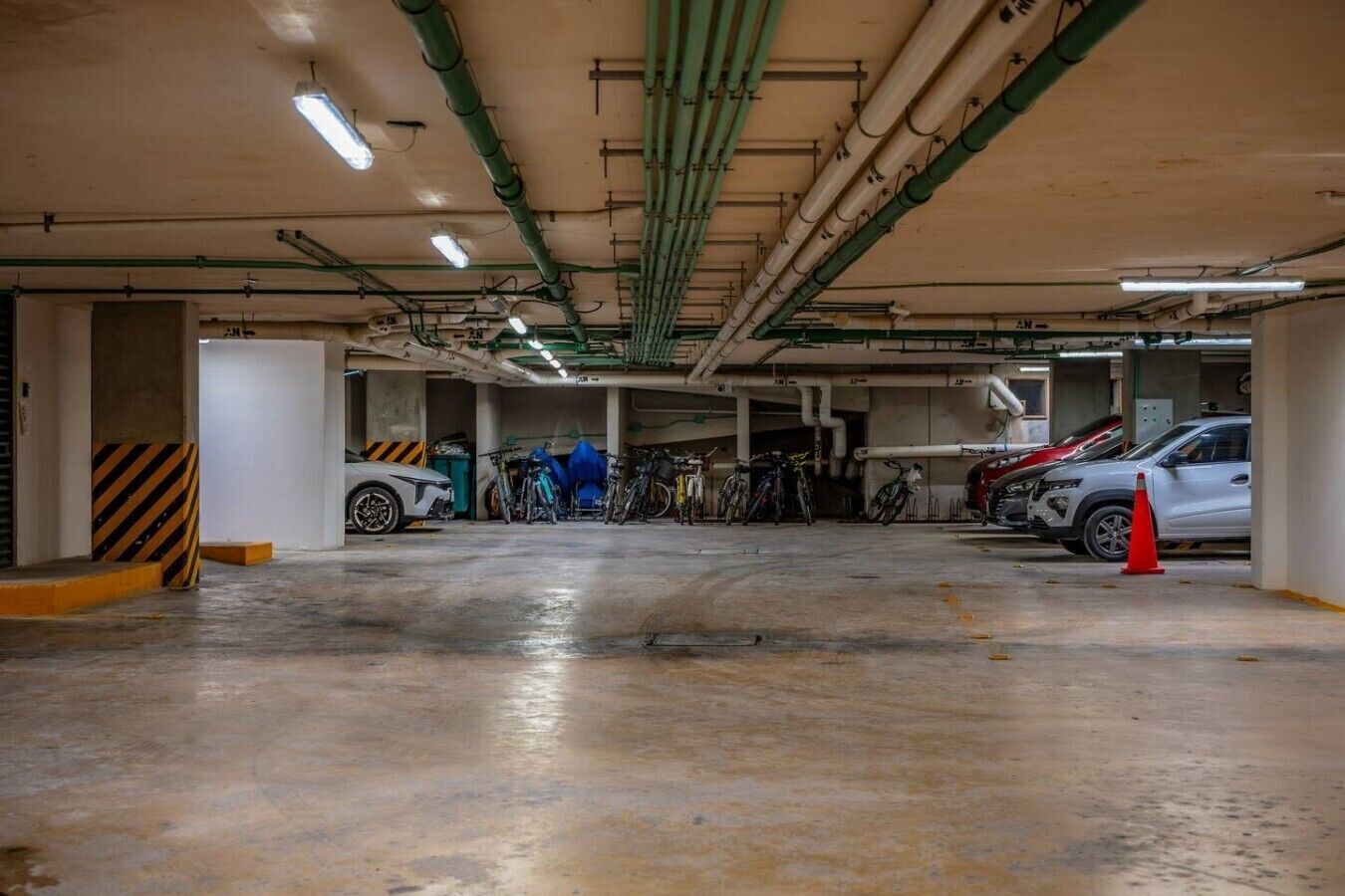 Een parkeergarage met meerdere niveaus, betonvloeren en leidingen aan het plafond.