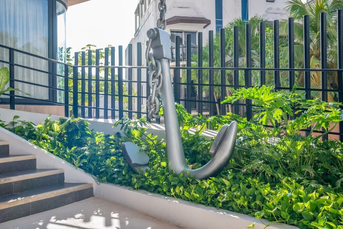 Una escalera que lleva a un edificio con una valla metálica y follaje.