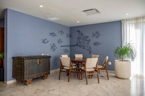 A dining area with a table and chairs, a decorative cabinet, and a large potted plant. - King Studio | Oceanview Pool & Gym | Free Parking (Playa del Carmen)
