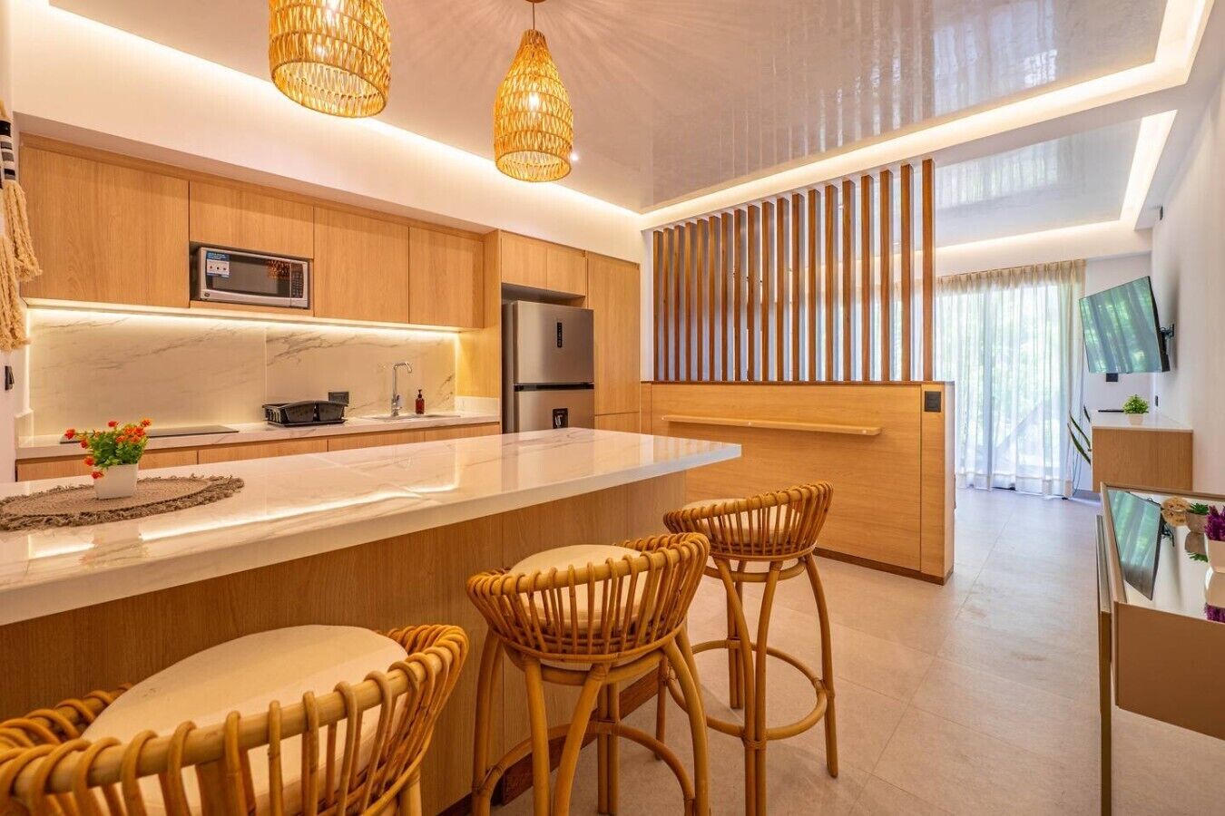 Cozinha moderna com ilha central, armários de madeira e geladeira embutida.
