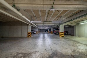 A multi-level parking garage with concrete pillars and fluorescent lighting. - Stylish 1BR | Gym, Rooftop Pool & Lounge w/Parking (Playa del Carmen)