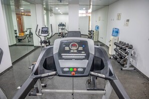 A gym with a ProForm elliptical machine, a treadmill, and a rack of dumbbells. - Stylish 1BR | Gym, Rooftop Pool & Lounge w/Parking (Playa del Carmen)