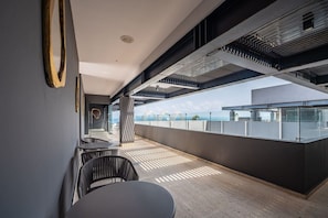 Un espace intérieur au design moderne, comprenant une longue table et des chaises, un sol à motifs et une vue sur le paysage urbain grâce à de grandes fenêtres.
