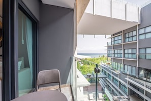 A balcony with a view of the ocean, a chair, and a table. - Luxury Beach Condo w/Rooftop Pool, Gym & Parking (Playa del Carmen)