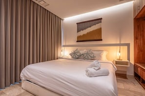 A hotel room with a large bed, a headboard with a painting, two bedside lamps, and a wooden cabinet. - Luxury Beach Condo w/Rooftop Pool, Gym & Parking (Playa del Carmen)