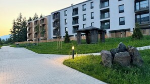 A modern residential building with multiple balconies, a paved pathway, and a small garden area. - Lovely 1-bedroom apartment in Gerlachov perfect for a relaxing stay (Gerlachov)