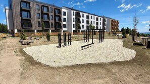 A modern building with multiple balconies and a playground area with exercise equipment. - Lovely 1-bedroom apartment in Gerlachov perfect for a relaxing stay (Gerlachov)