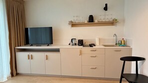 A modern kitchen with a flat-screen TV, a coffee maker, a toaster, and a sink with a faucet. - Lovely 1-bedroom apartment in Gerlachov perfect for a relaxing stay (Gerlachov)