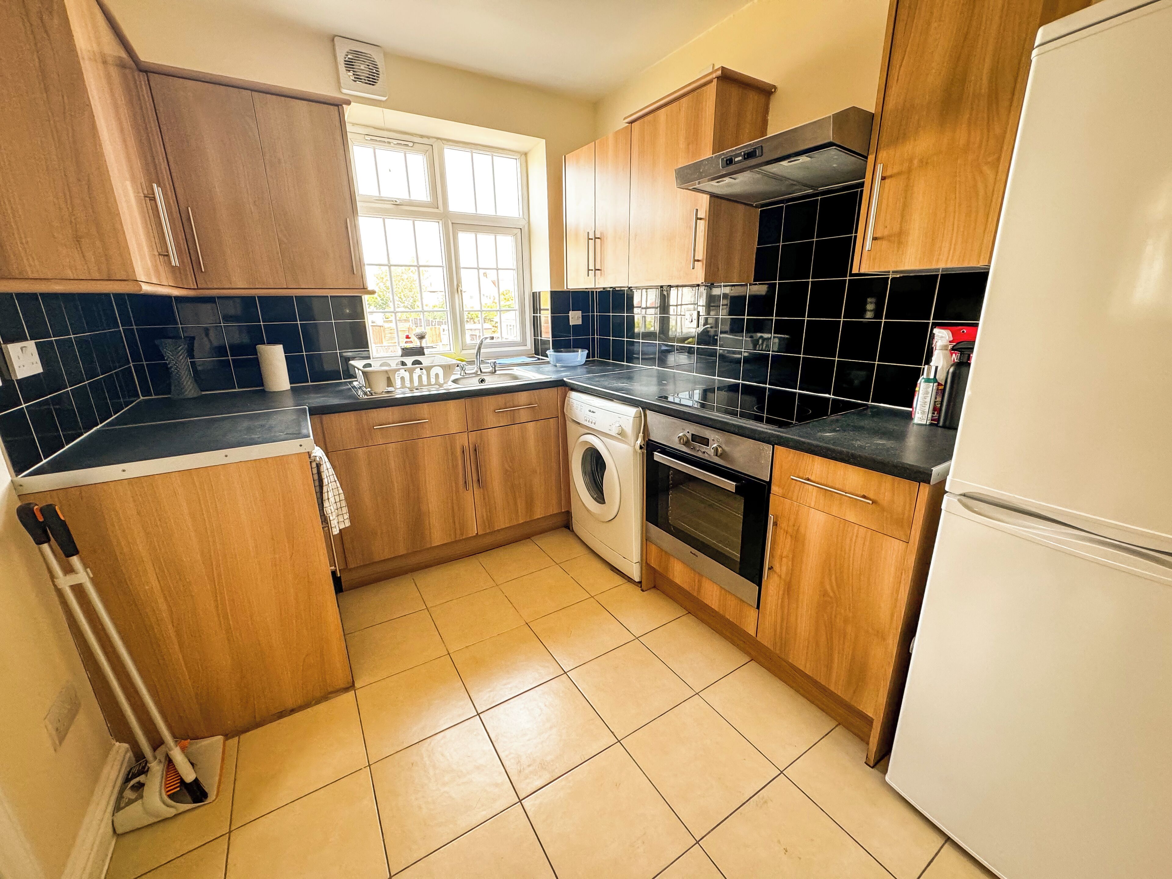 Eine Küche mit Holzausstattung, einer Waschmaschine, einem Backofen und einem Kühlschrank.