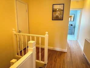 A hallway with a wooden floor, a white railing, and a door at the end. - 3 Bedroom 2 Bathroom flat. 15mins walk to Wembley Stadium. Secure gated parking. (Wembley)