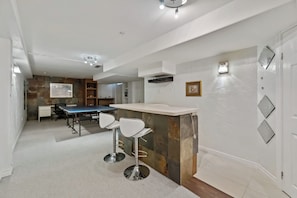 A modern kitchen with a bar area, bar stools, and a dining table. - Stylish 2-bedroom, 3-bath townhouse about 15 minutes from Niagara Falls. (St. Catharines)