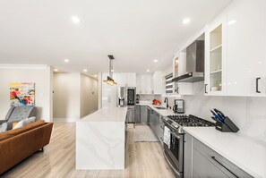 A modern kitchen with white cabinetry, stainless steel appliances, and a central island. - Luxury Spa Escape with Pool & Jacuzzi [Near Rogers Stadium] (Toronto)