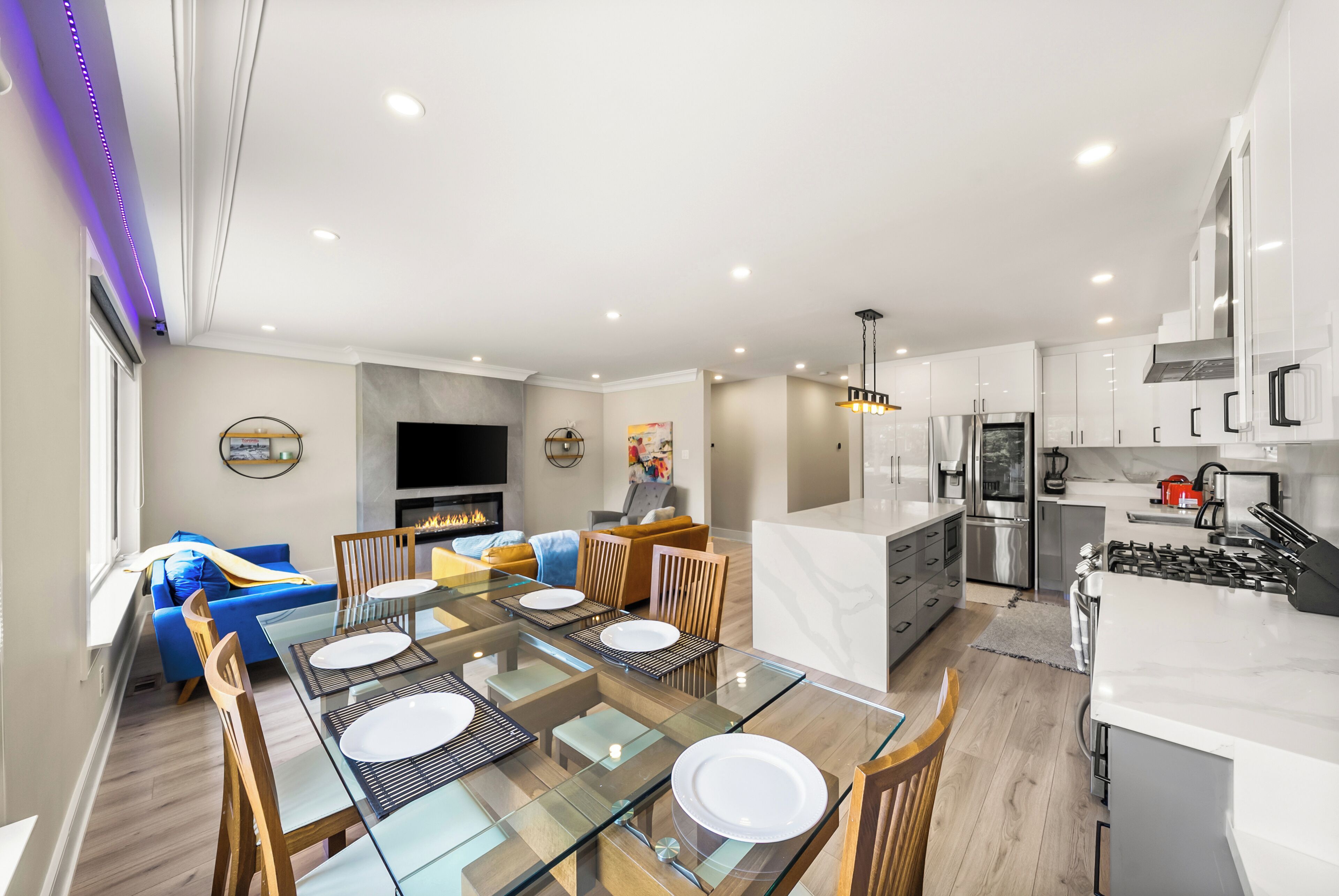 A modern kitchen with white cabinets, stainless steel appliances, and a glass dining table.