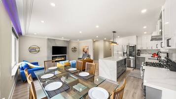 A modern kitchen with white cabinets, stainless steel appliances, and a glass dining table.