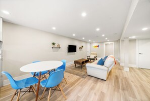 A modern living room with a white sofa, blue chairs, a coffee table, and a flat-screen TV on the wall. - Luxury Spa Escape with Pool & Jacuzzi [Near Rogers Stadium] (Toronto)