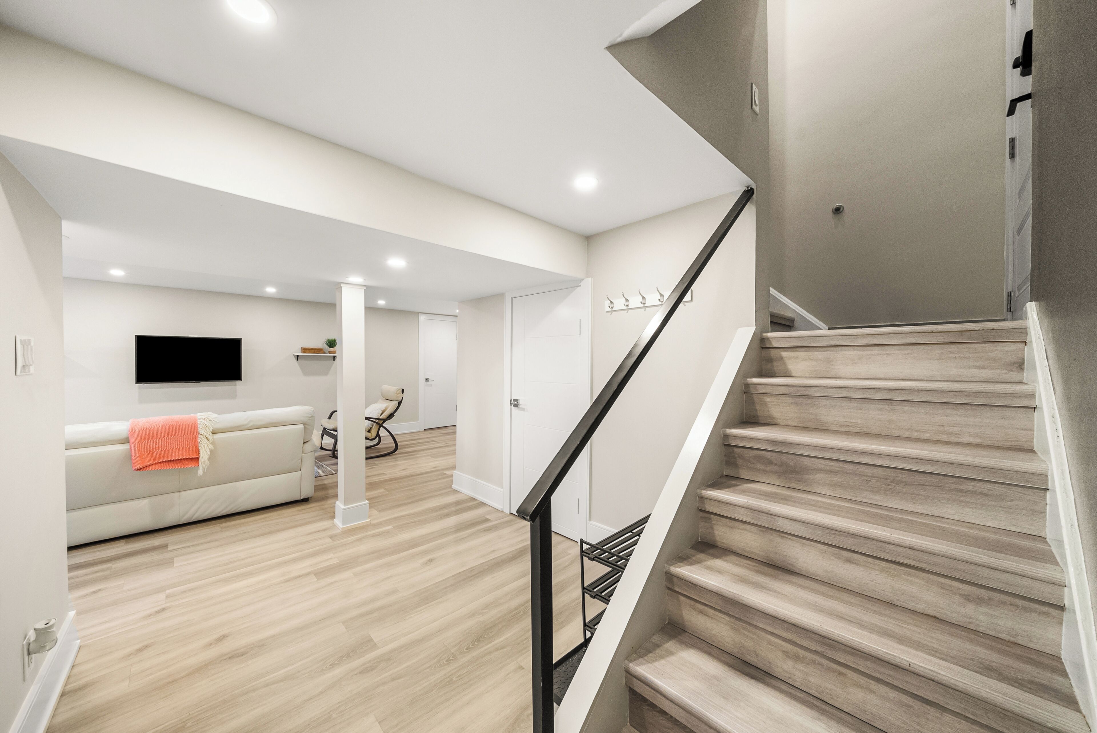A modern interior with a staircase, a sofa, and a flat-screen TV.