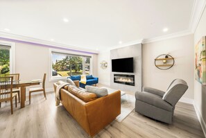 A modern living room with a sofa, armchair, and a flat-screen TV mounted on the wall. - Luxury Spa Escape with Pool & Jacuzzi [Near Rogers Stadium] (Toronto)