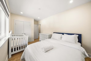 A bedroom with a crib, a dresser, and a bed with white bedding. - Luxury Spa Escape with Pool & Jacuzzi [Near Rogers Stadium] (Toronto)