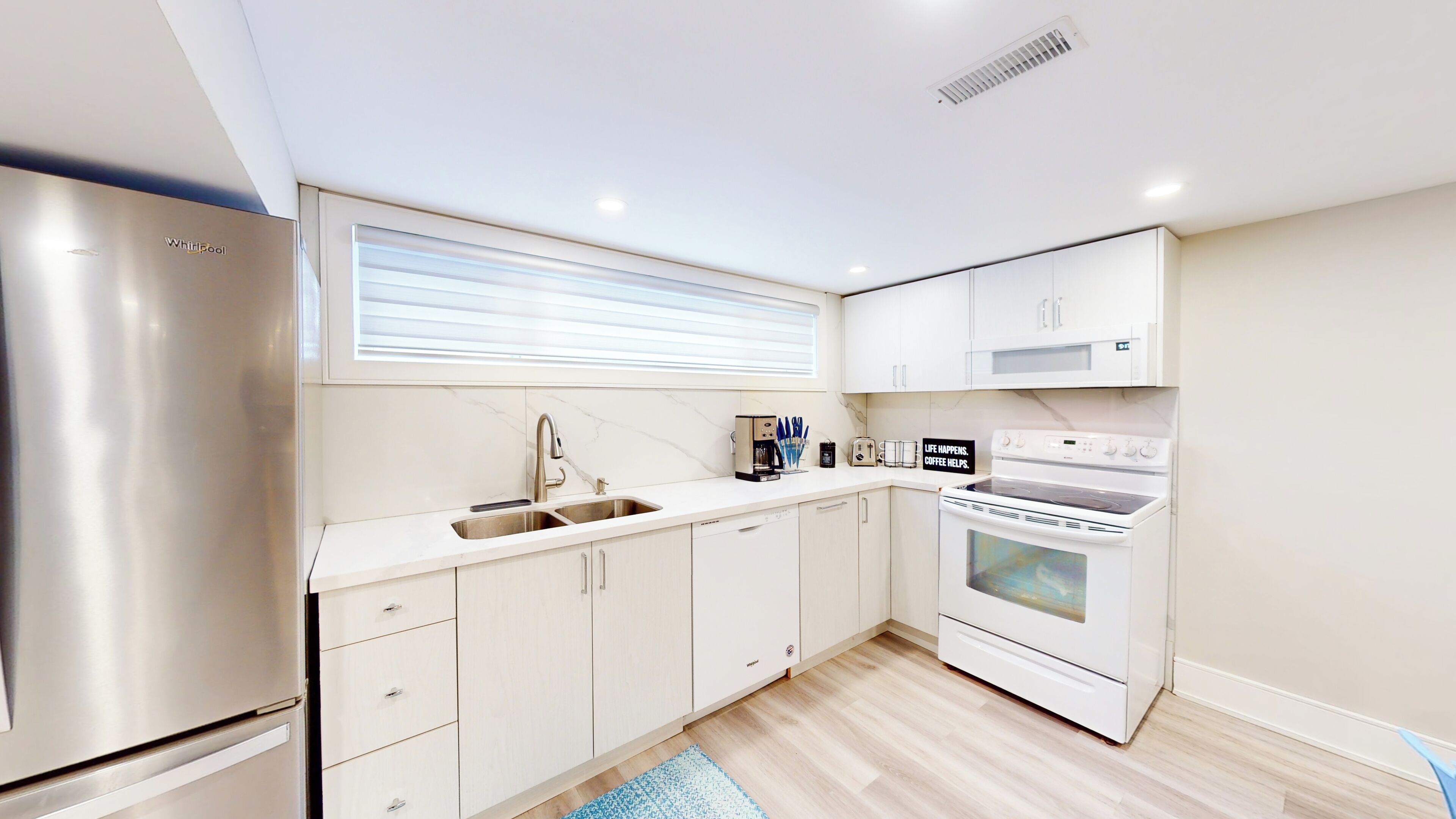 A modern kitchen with a stainless steel refrigerator, a built-in oven, and a coffee maker.