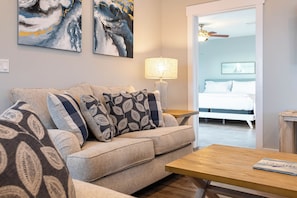 A living room with a sofa, a coffee table, a lamp, and a bed in the background. - Pet Friendly with Gulf Views- 50 Sea Turtle by Royal Destinations (Santa Rosa Beach)
