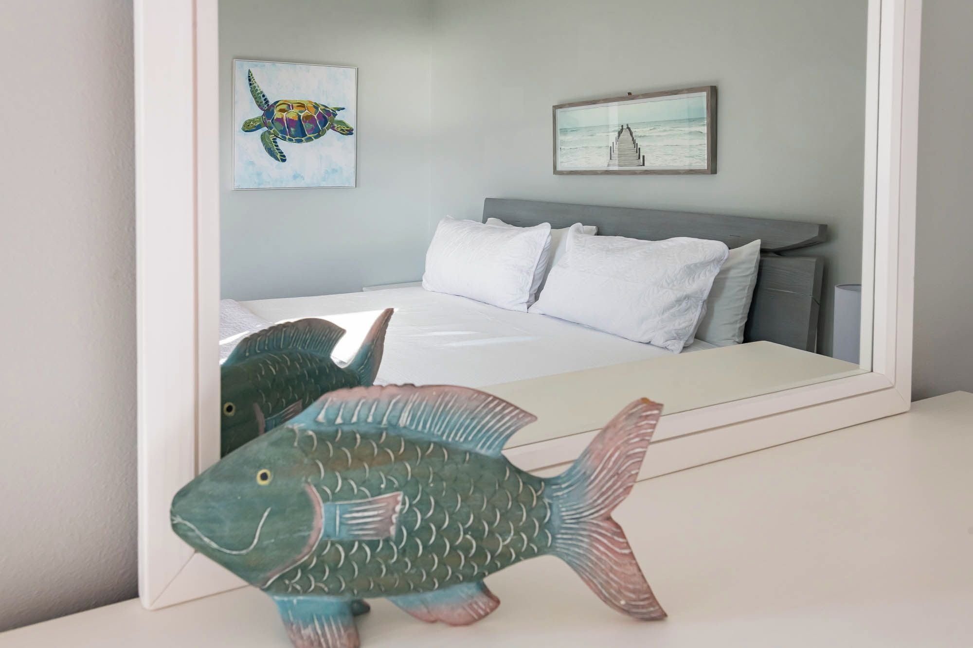 A bedroom with a bed, pillows, a headboard, and two wall art pieces.