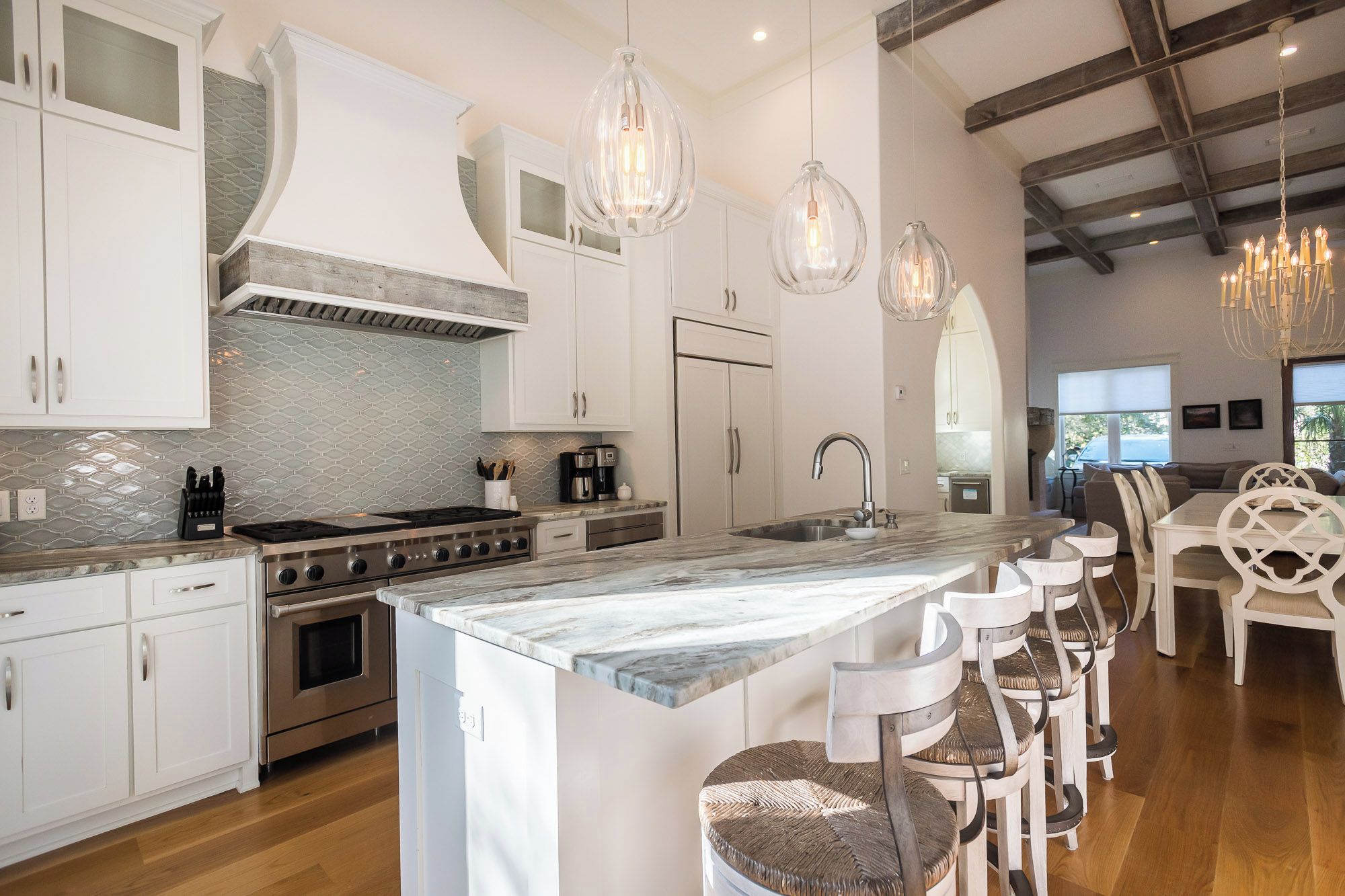 A modern kitchen with white cabinetry, a large island with bar stools, and pendant lighting.
